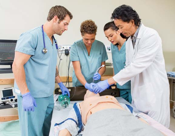 Four medical professionals practicing CPR techniques on a manikin during a training session.